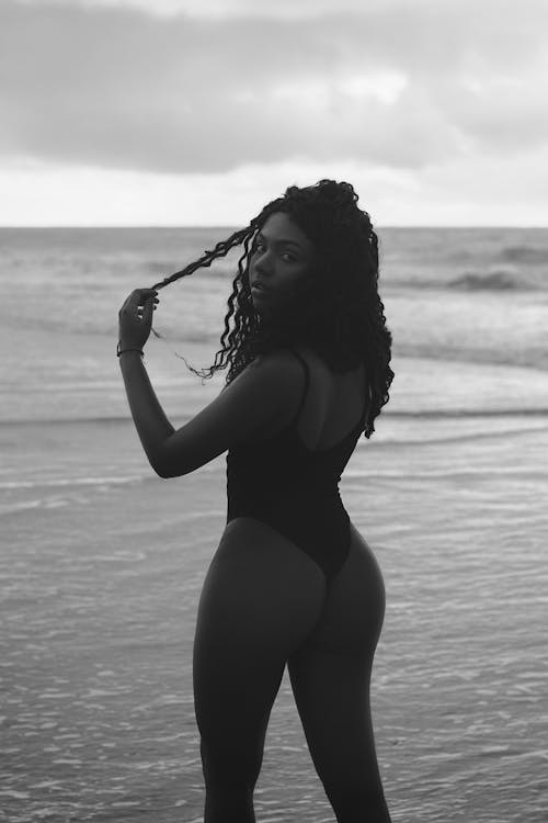 A woman in a black swimsuit standing on the beach
