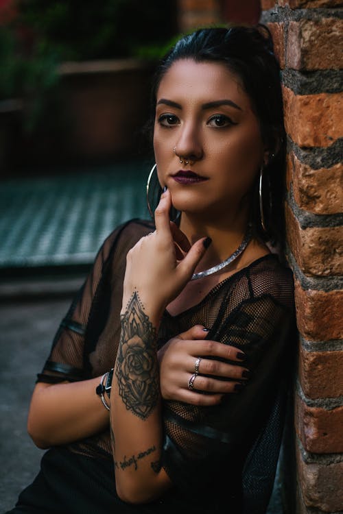 Photo of Tattooed Woman Leaning on Bricked Wall · Free Stock Photo