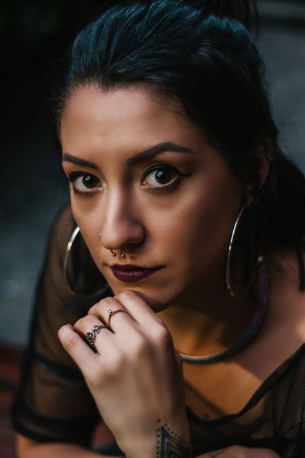 Close-up portrait of a woman with hoop earrings and septum piercing in São Paulo, capturing a pensive expression.