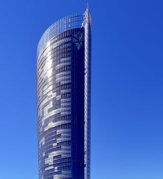 一座现代摩天大楼的弯曲玻璃立面映衬在晴朗的蓝天下