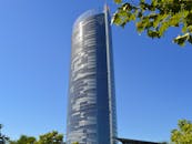 一座醒目的玻璃摩天大楼高耸在清澈的蓝天下，点缀着叶子的装饰