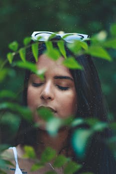 绿叶丛中，一位戴太阳镜的女子闭目养神，神情放松