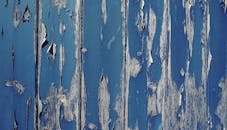 蓝色油漆风化木墙的特写与剥落的油漆纹理