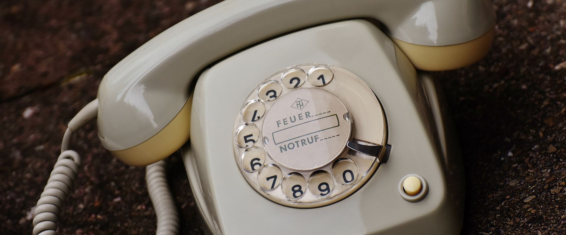Close-up of an old rotary dial telephone with cream tones and German labeling.