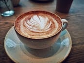 在一个舒适的咖啡馆里，特写的卡布奇诺咖啡与精致的拿铁艺术相映成趣