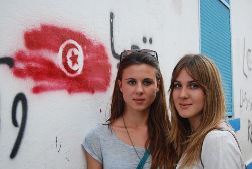 Free Two women pose in front of graffiti featuring the Tunisian flag in Tunis. Stock Photo