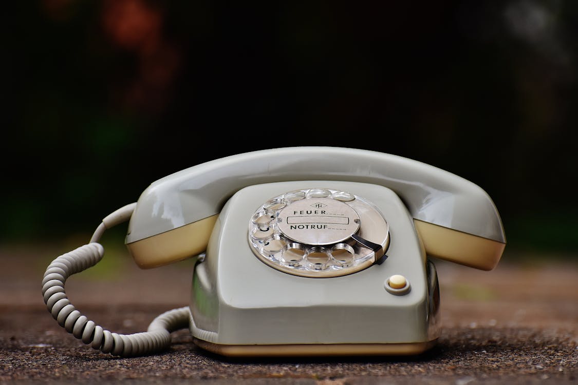 Gray Rotary Telephone on Brown Surface