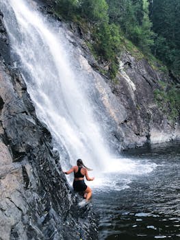 一位女士在挪威欣赏壮丽的瀑布景色，展现了自然之美与冒险精神