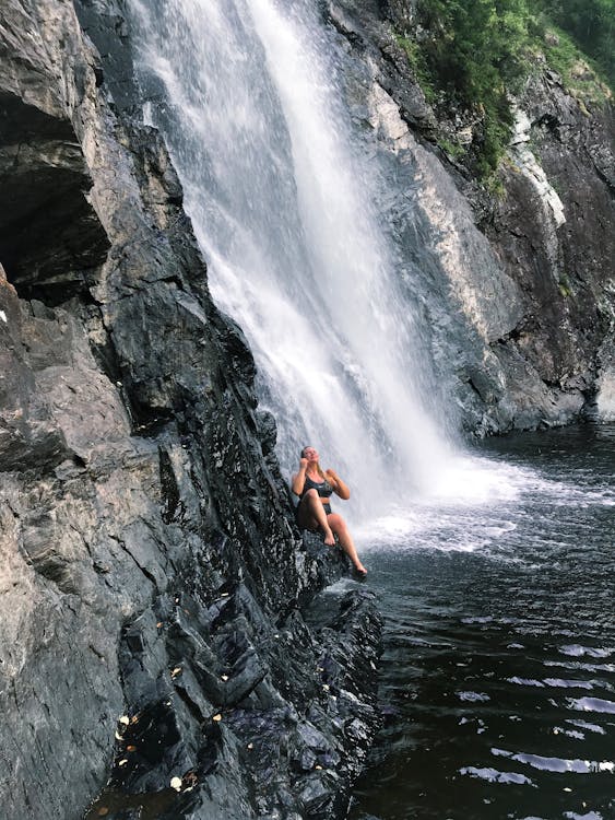 Persona Sentada Sobre Una Roca Cerca De Las Cataratas Del Agua