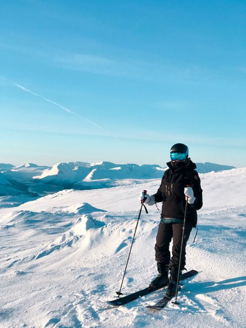 A skier enjoys the snow-covered mountains of Norway under a bright, clear sky.