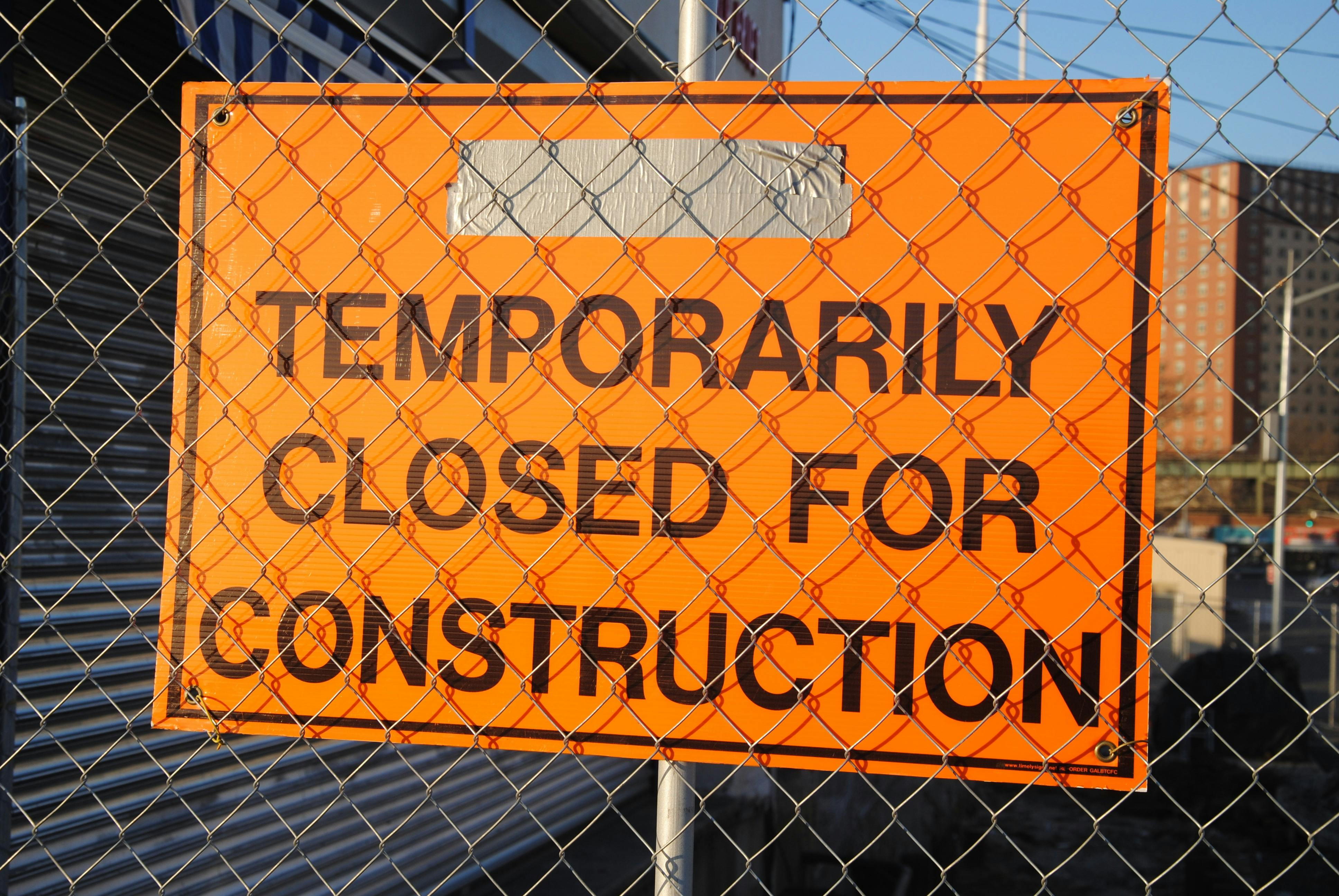 Image of a sign behind a chainlink fence that has the text TEMPORARILY CLOSED FOR CONSTRUCTION  - from pexels.com