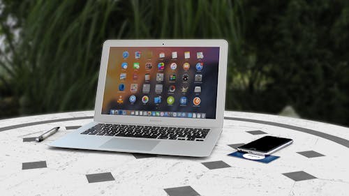 включенный Macbook Air на бело серой поверхности