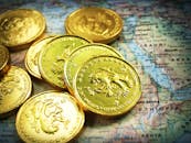 世界地图上放着一堆闪亮的金币，象征着全球财富