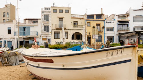 A boat on the beach in front of a building