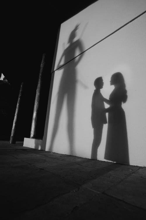 A shadow of a woman and man standing in front of a wall