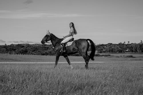 A black and white photo of a girl riding a horse