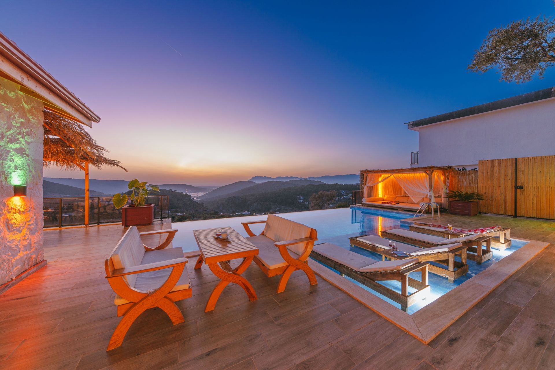 A villa patio and infinity pool overlooking mountains at sunset
