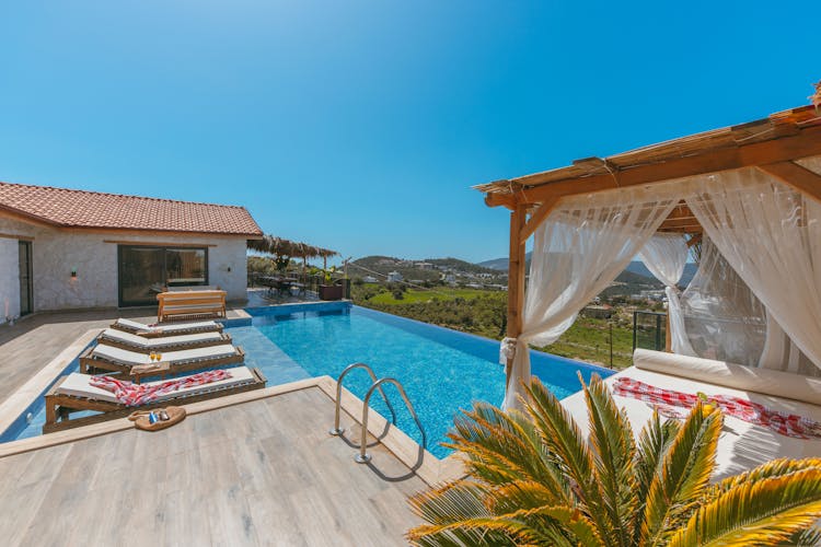 Deckchairs And Swimming Pool On Patio Of Mansion