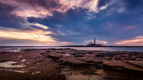 Rocky Beach Near Lighthouse on Ocean Shore