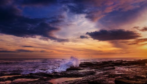 A sunset over the ocean with waves crashing