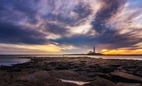 A lighthouse is seen at sunset on the beach