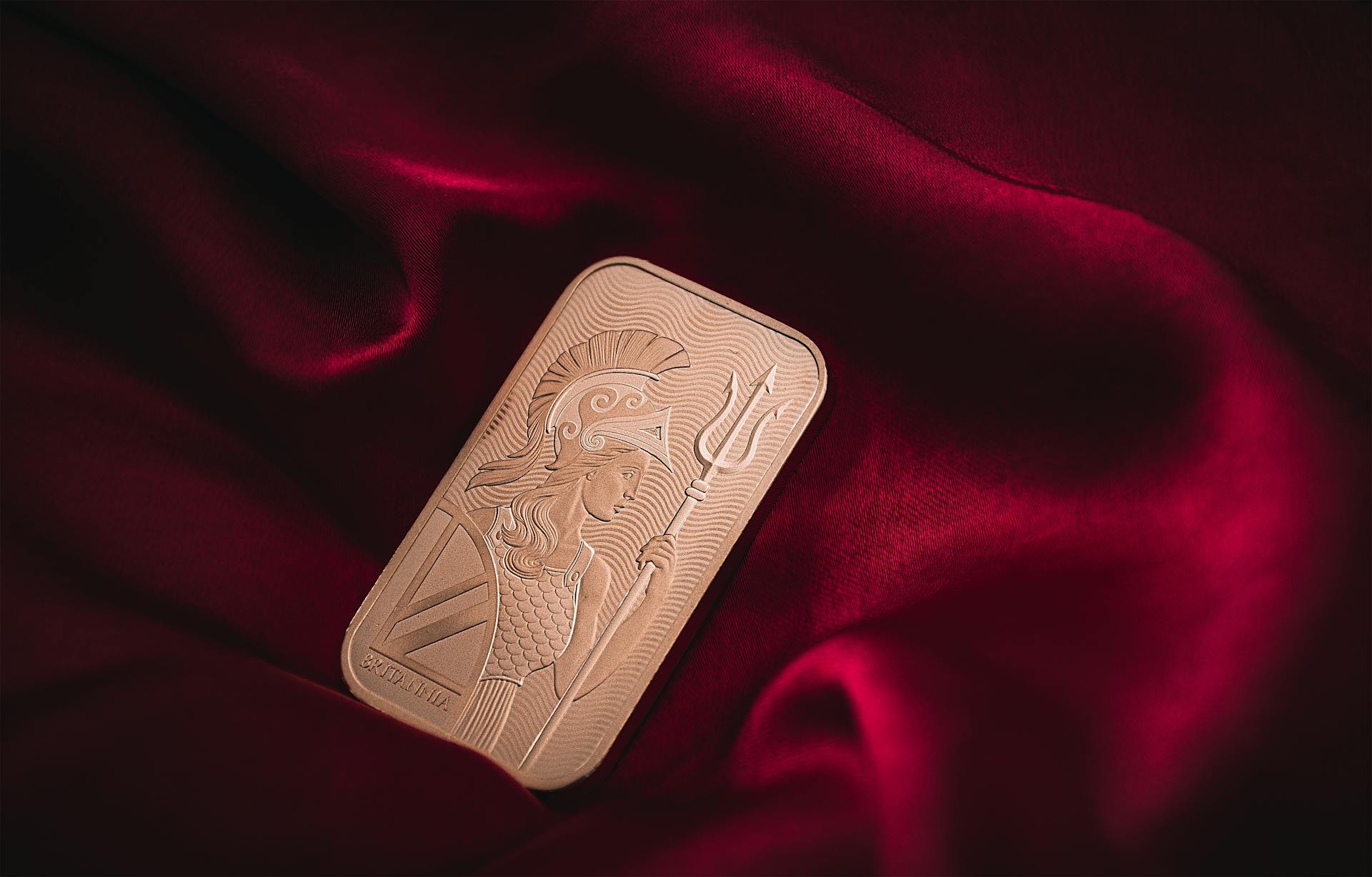 Close-up of a golden bar with ancient warrior engraving on red velvet.