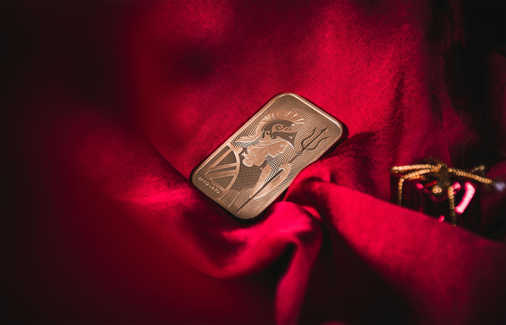 A beautifully detailed gold bar resting on luxurious red velvet, symbolizing wealth and elegance.