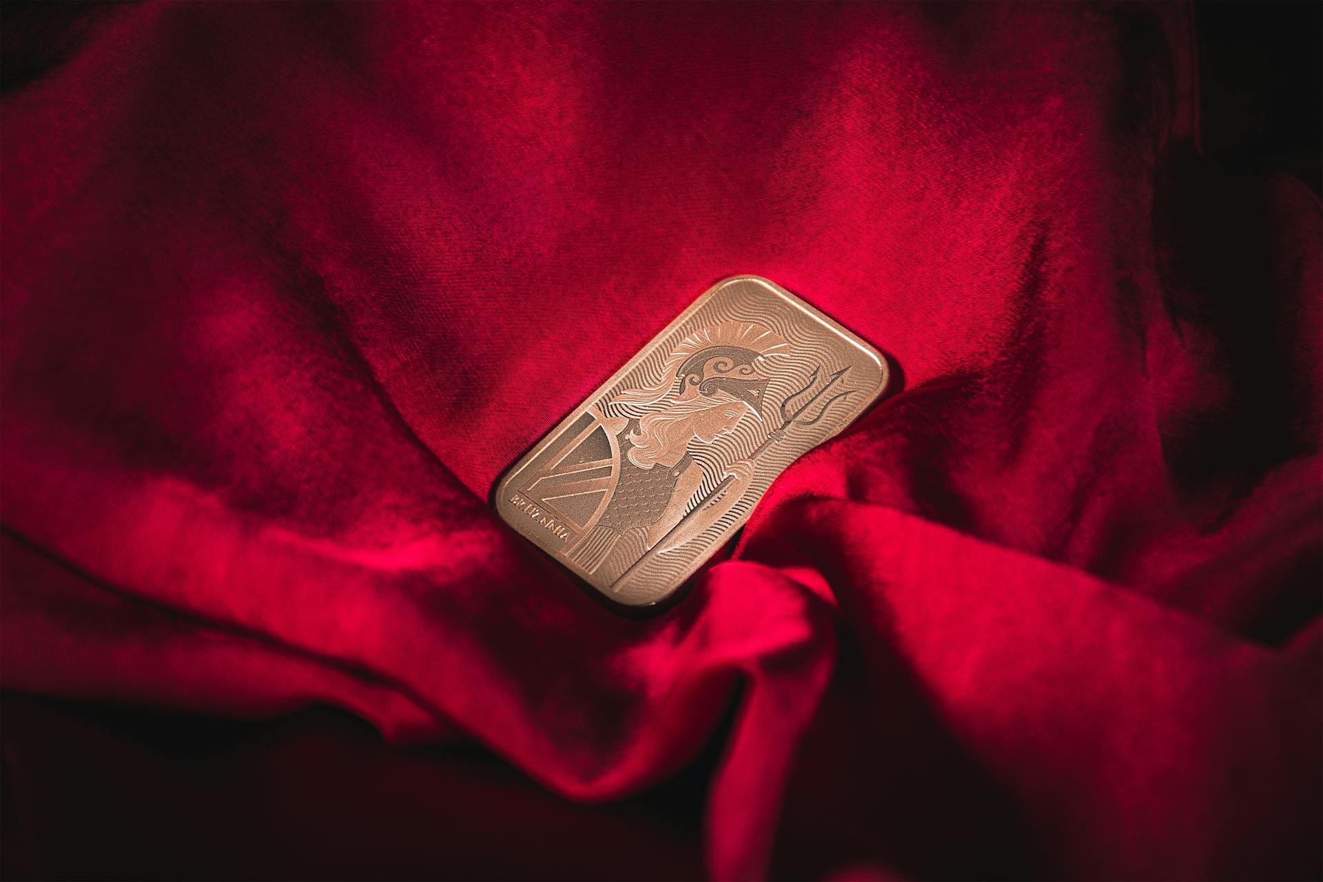 Close-up of a gold bar resting on vibrant red velvet, symbolizing wealth and luxury.