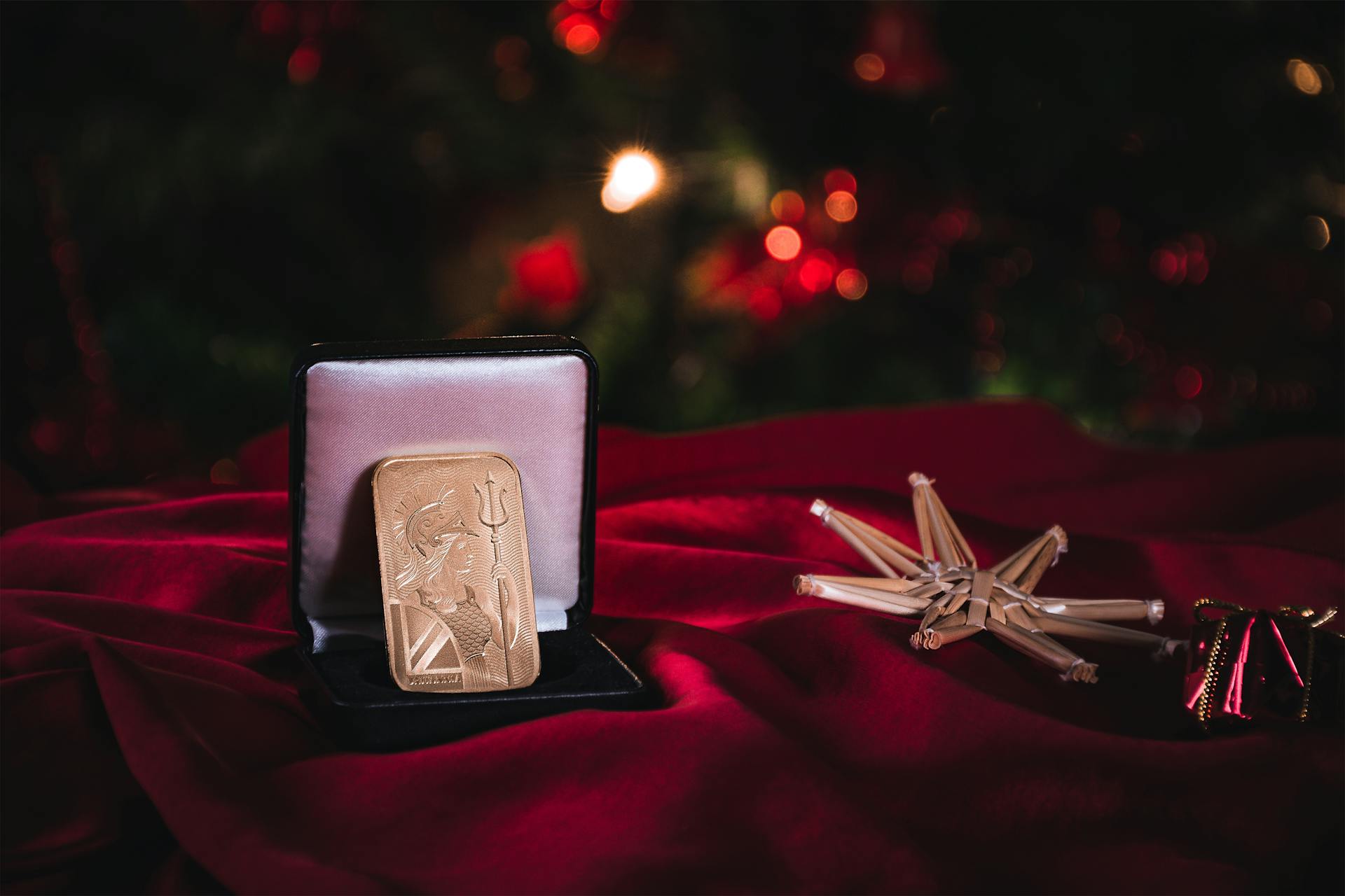 Gold bar displayed in a velvet box with festive Christmas background, symbolizing luxury and investment.