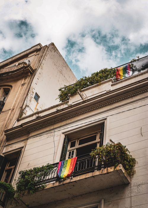 Free City building with balconies displaying rainbow flags, showcasing diversity and urban life. Stock Photo