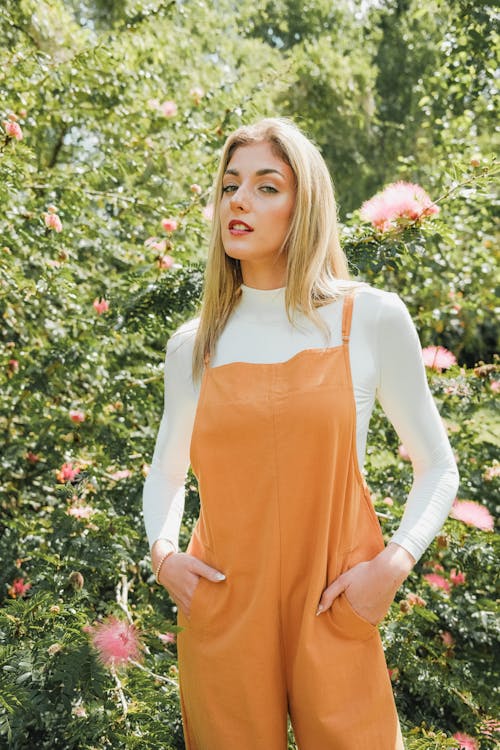 Pretty Blonde Woman in Orange Overalls in Garden