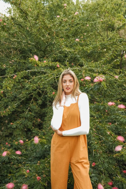 Free A woman in overalls posing in front of a bush Stock Photo