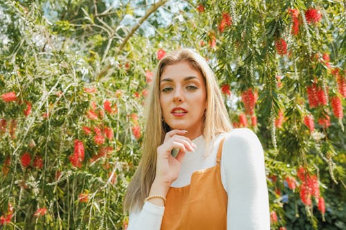 Free A woman in an orange dress and white shirt posing in front of a tree Stock Photo