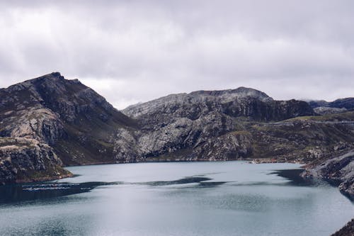 A lake surrounded by mountains and a cloudy sky