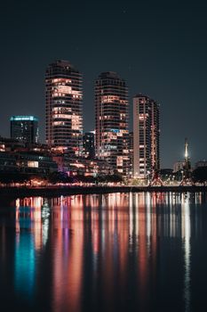A modern city skyline reflecting beautifully on the harbor at night.