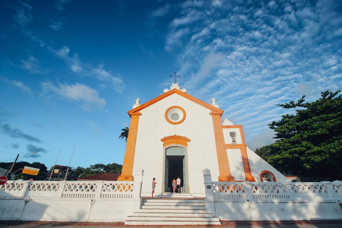 Free People In Front Of White And Orange Church Stock Photo