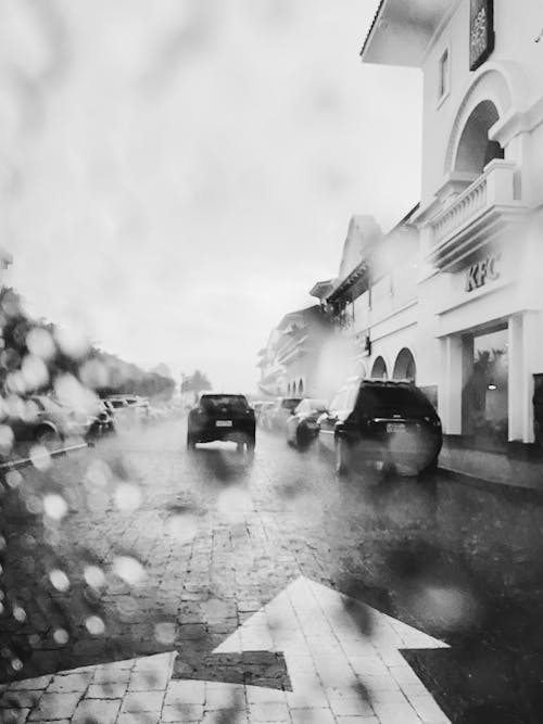 A black and white photo of a street with cars