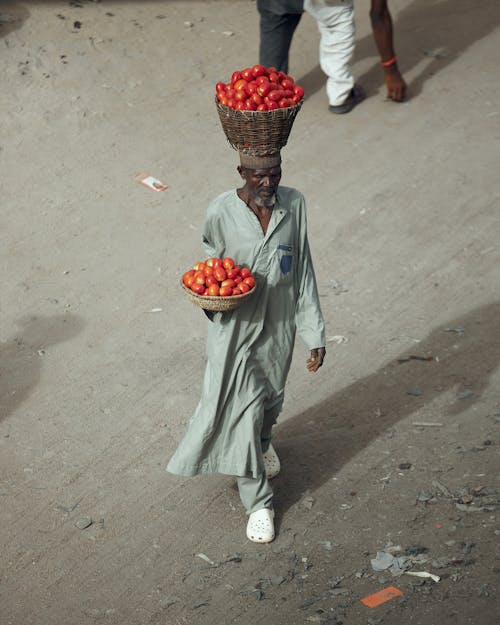 A man carrying a basket of tomatoes on his head