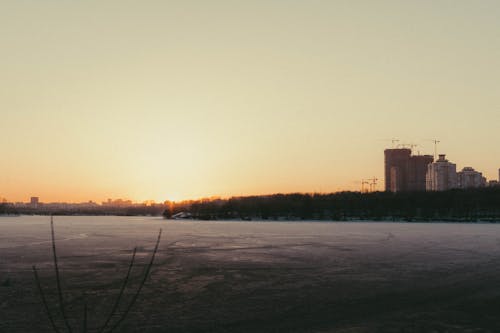 frozen city reservoir at sunset against the background of houses under construction 