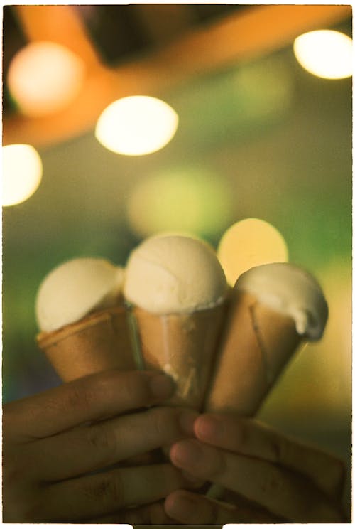 A person holding three ice cream cones in their hands