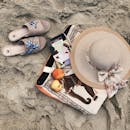 平坦的沙滩上铺着帽子和拖鞋这些海滩必需品，充满了完美的夏日氛围