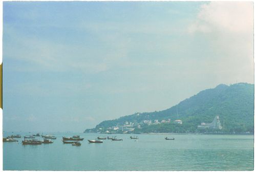 Free Peaceful seaside image with boats, lush hills, and a coastal village. Stock Photo