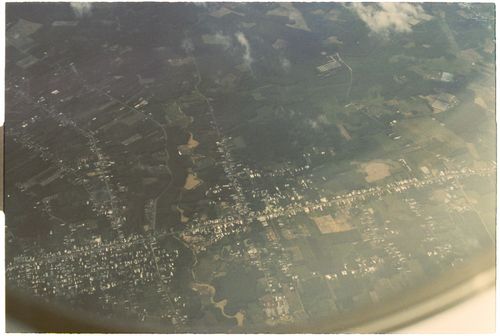 Free High-altitude view of a town and surrounding fields from an airplane window, showcasing landscape details. Stock Photo