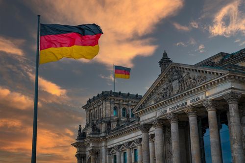 Free Iconic Reichstag building in Berlin, Germany with national flags at sunset, showcasing architectural beauty. Stock Photo