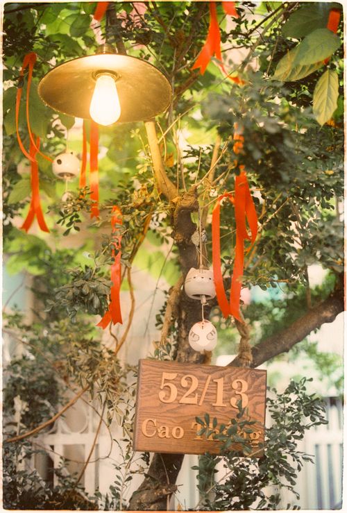 Free Charming outdoor scene with a glowing lamp, red ribbons, and a wooden sign surrounded by lush leaves. Stock Photo