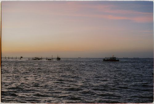 Free Enjoy the tranquil view of boats sailing under a captivating sunset sky. Stock Photo