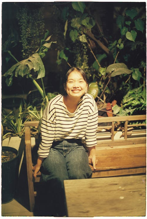 A woman sitting on a bench in front of plants