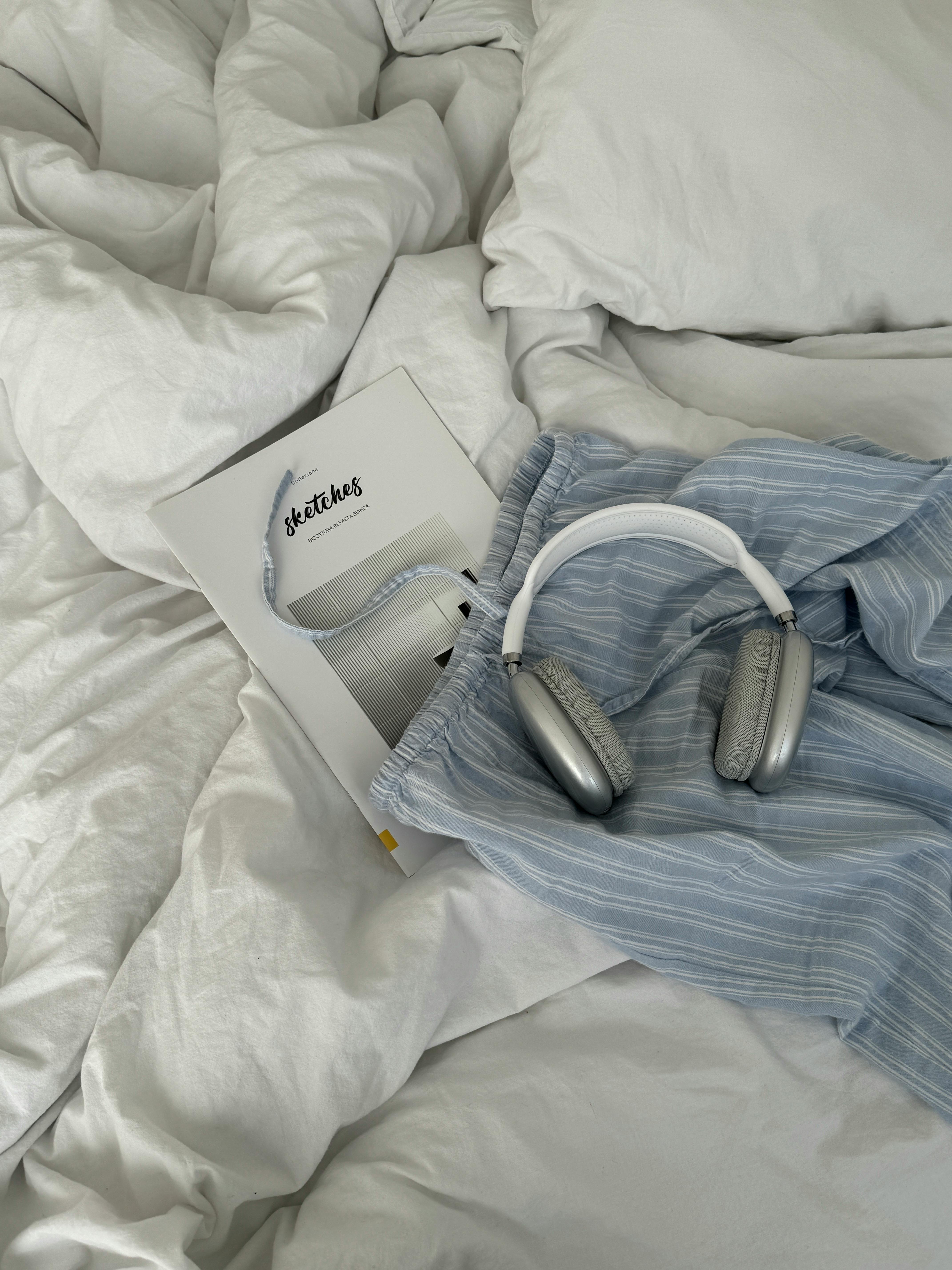 Relaxing setup with headphones and a book on a cozy bed, perfect for unwinding.