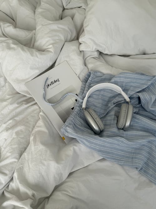 A book and headphones laying on top of a bed