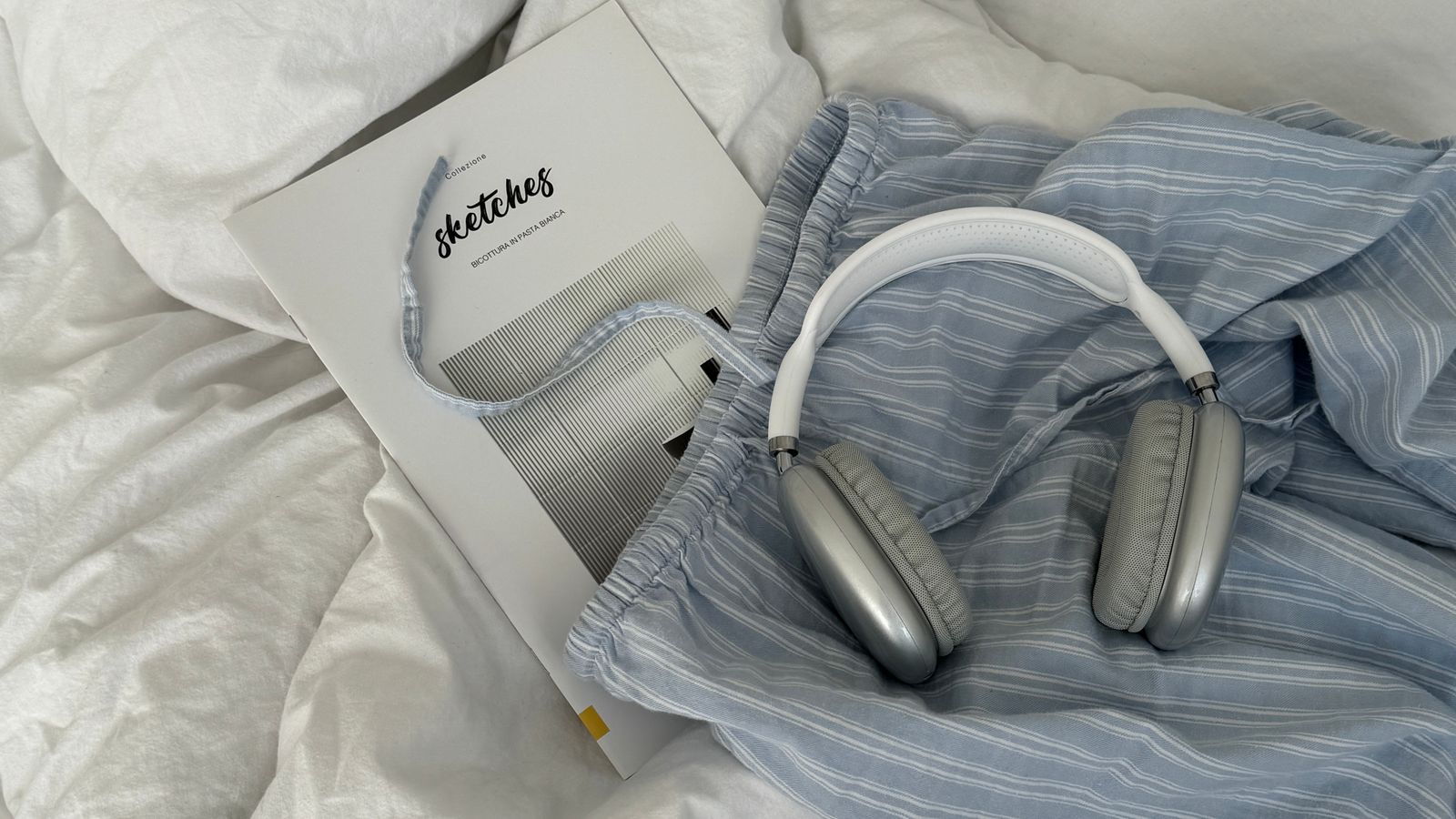 Headphones and a book resting on a cozy bed